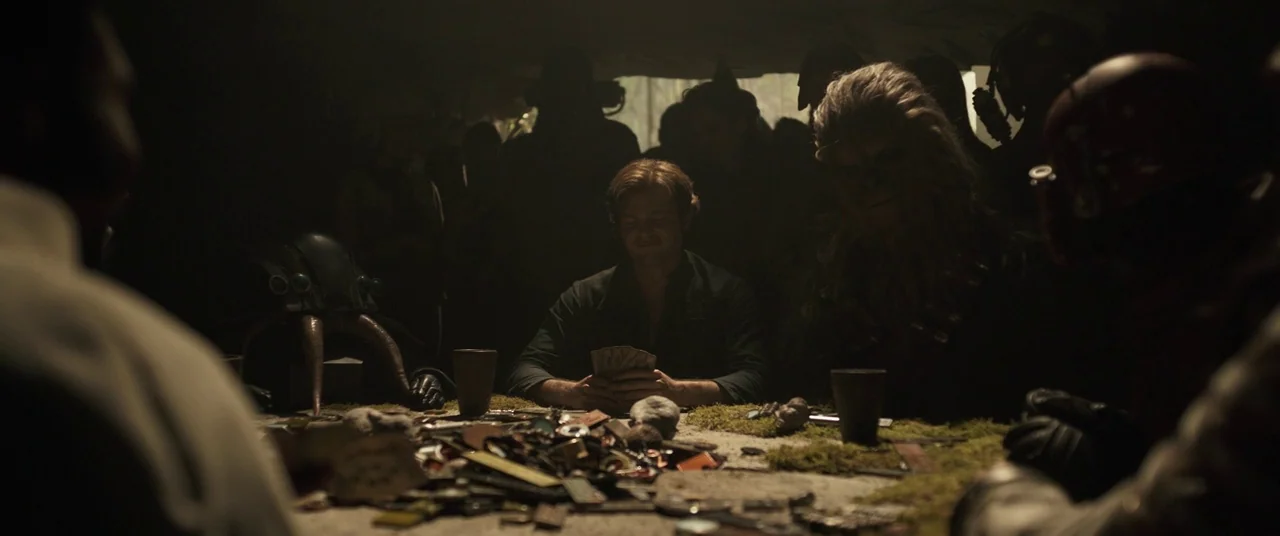Solo: A Star Wars Story (2018) movie still: medium — A dark, dimly lit setting with a stone table covered in various gaming items. Multiple figures…