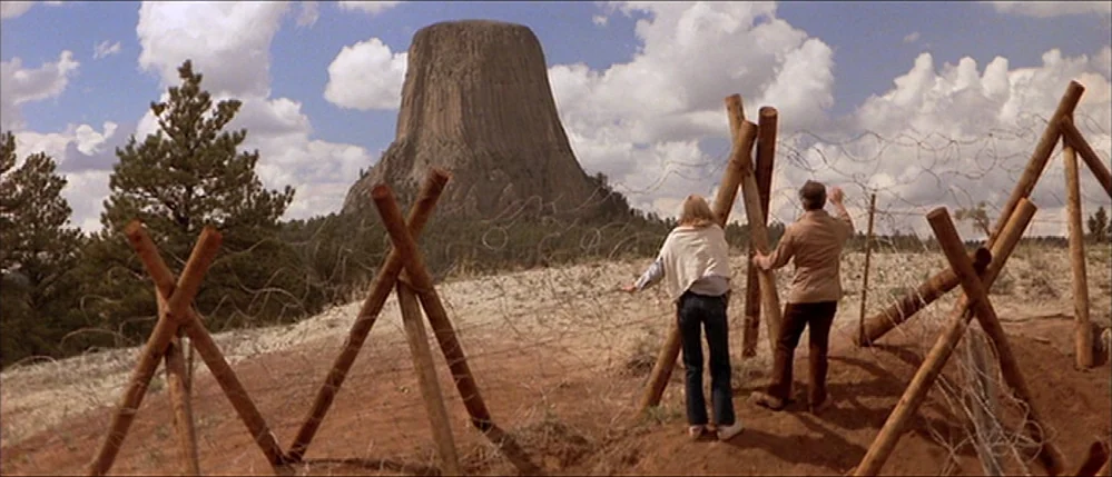 Close Encounters Of The Third Kind (1977) movie still: wide — A rural landscape features a large, flat-topped geological rock formation under a…