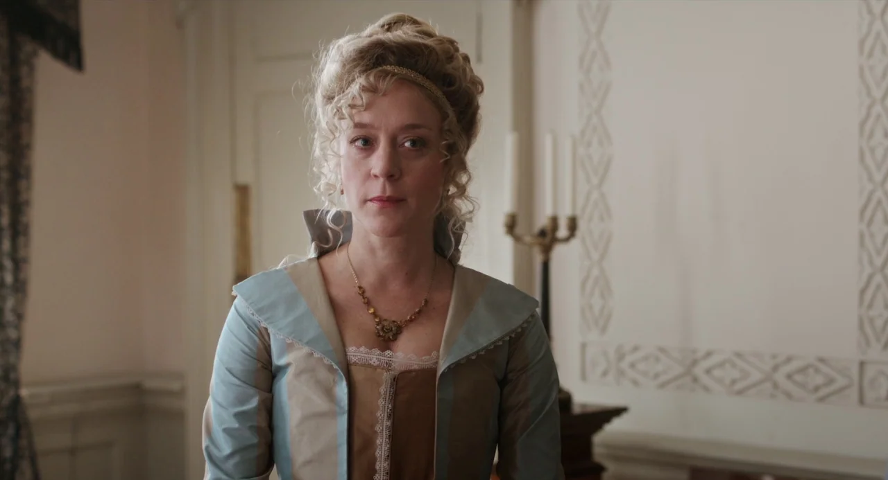 Love and Friendship (2016) movie still: medium — A well-lit room features classic period architecture with white decorative wall moldings. A woman…