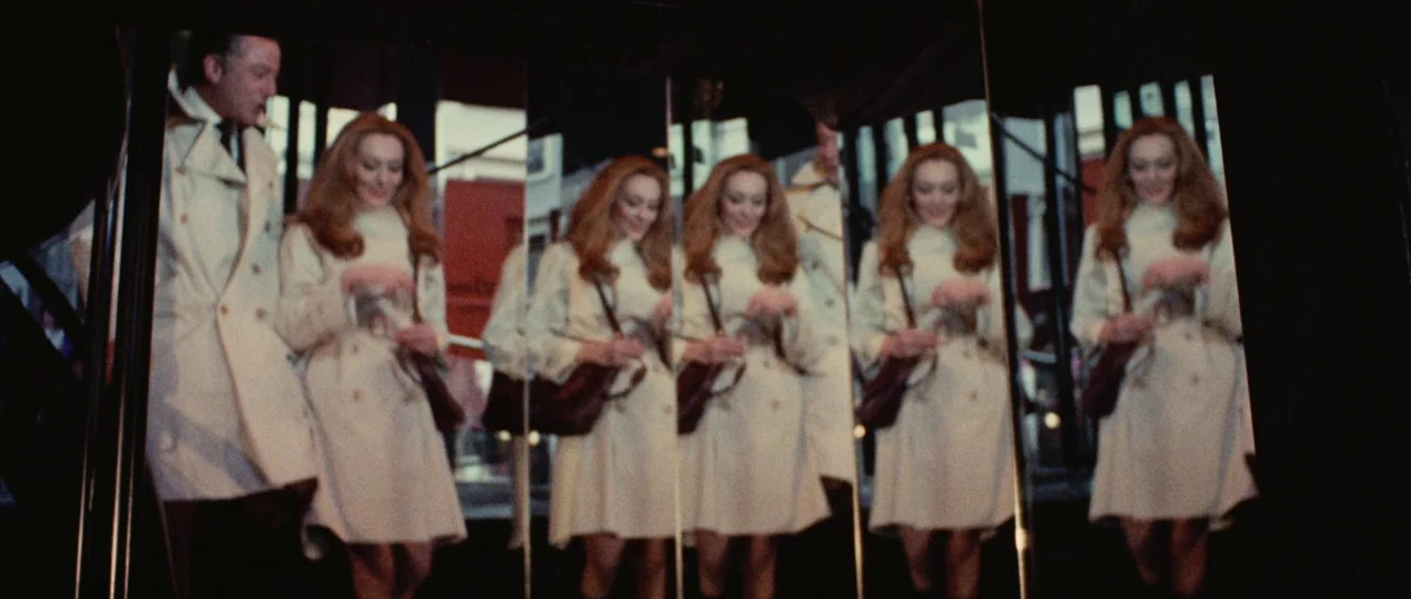 Death Walks On High Heels (1971) movie still: medium — A man and woman are reflected multiple times within an array of upright mirrors. The…