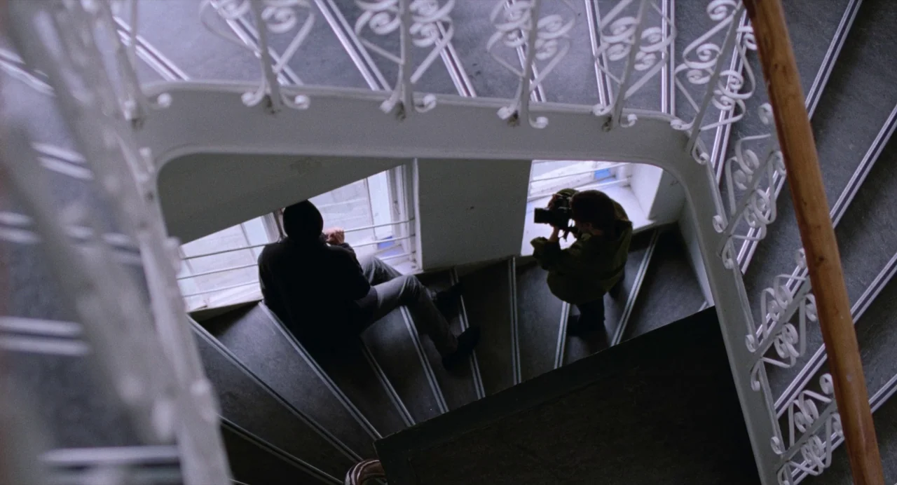 The Worst Person in the World (2021) movie still: wide — A curved indoor stairwell features white metal railings and grey steps near a window. A…