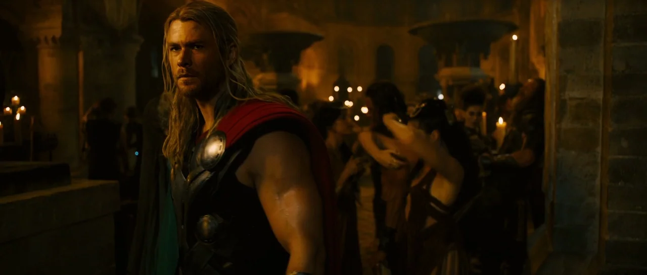 Avengers: Age of Ultron (2015) movie still: medium — A dimly lit stone hall features numerous lit candles and indistinct figures in the background.…