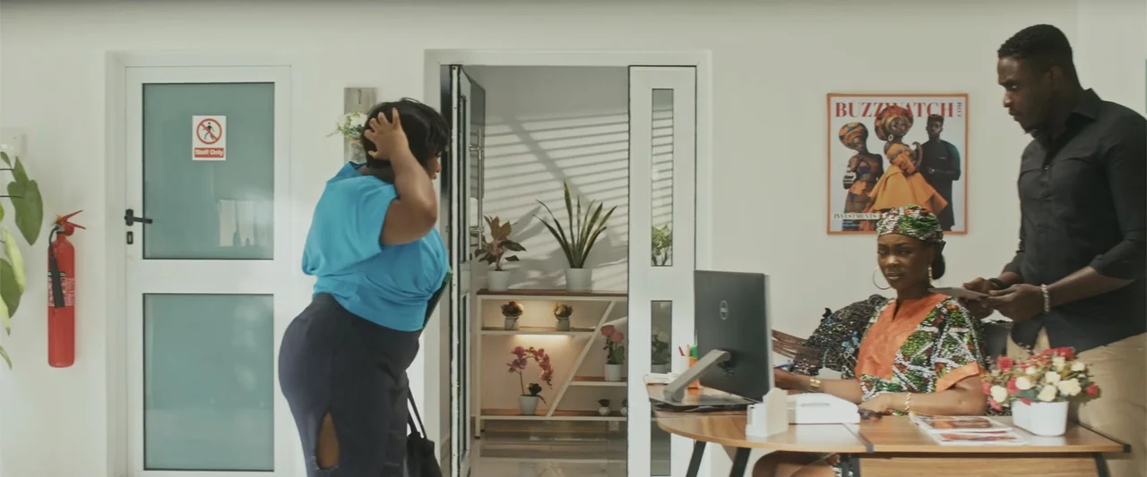 Casa De Novia (2024) movie still: medium — A modern, white-walled office reception area features large windows, potted plants, and minimalist decor.…