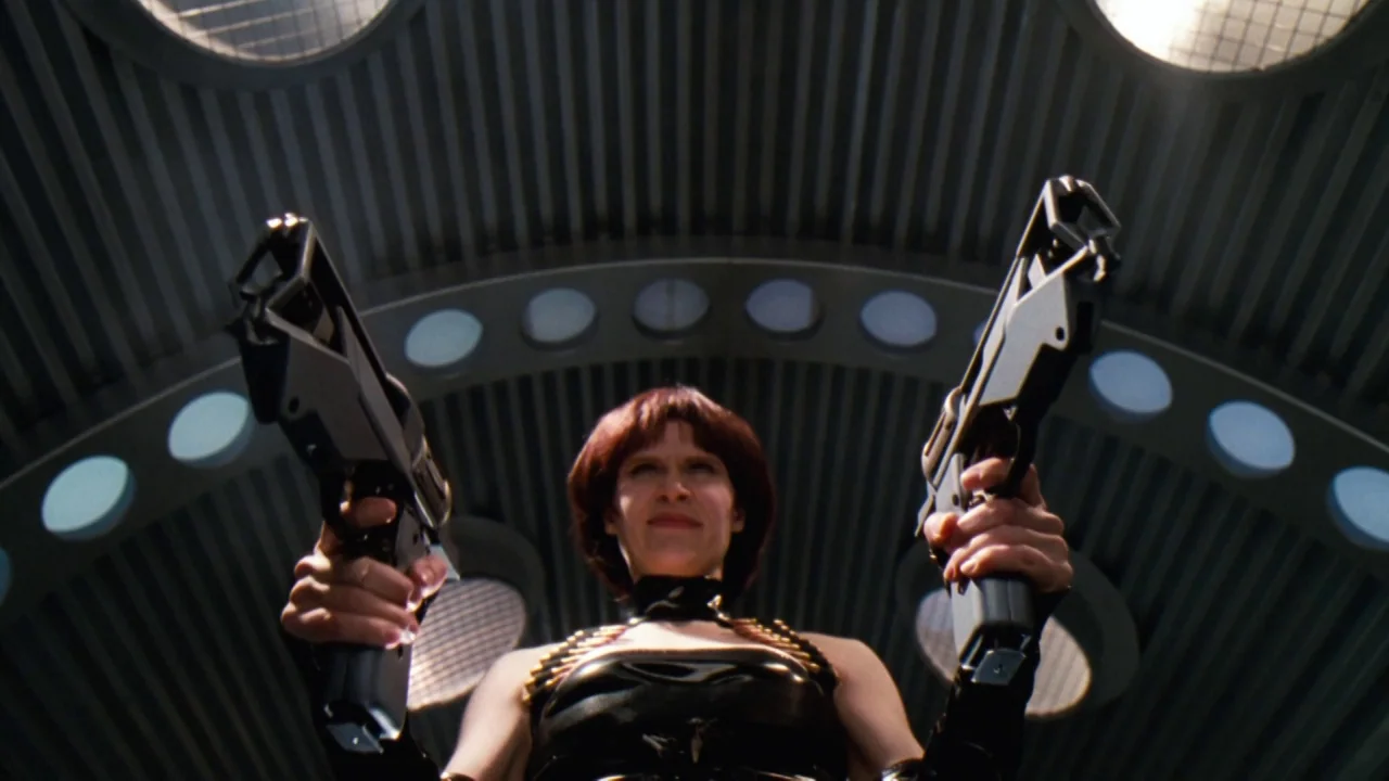 Jason X (2001) movie still: medium — A metallic industrial corridor features a curved, corrugated ceiling with recessed circular lights. A woman in…