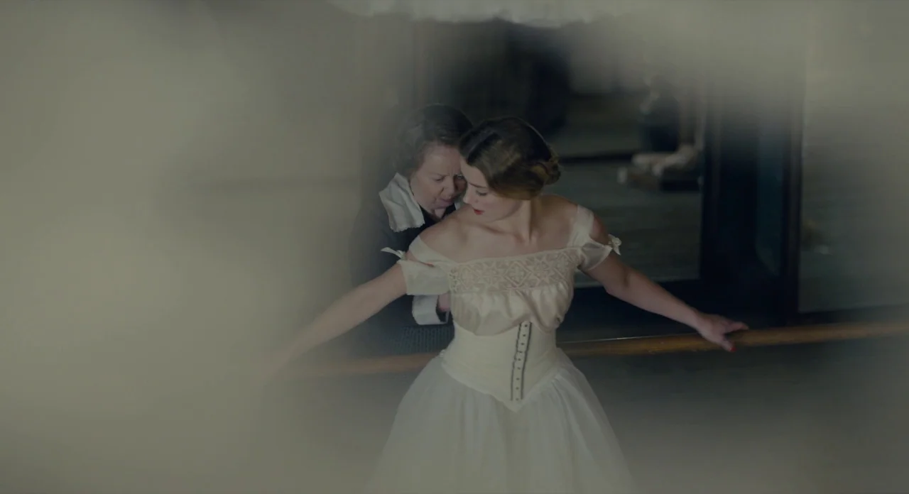 The Danish Girl (2015) movie still: medium — A wooden ballet studio with a practice barre stretching across the middle of the room. An older woman…