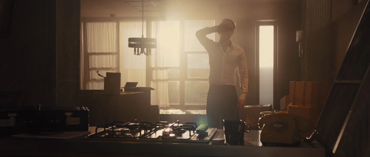 High-Rise (2015) movie still: fullbody — A living area features cardboard packing boxes and a central gas stovetop island. A man stands silhouetted…