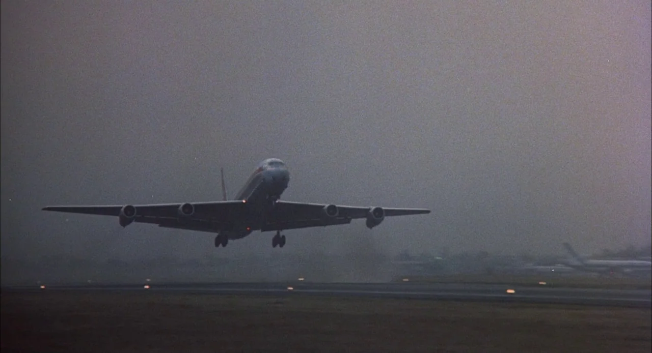 Bring Me The Head of Alfredo Garcia (1974) movie still: wide — A passenger jet lifts off from a concrete runway obscured by dense morning fog.…