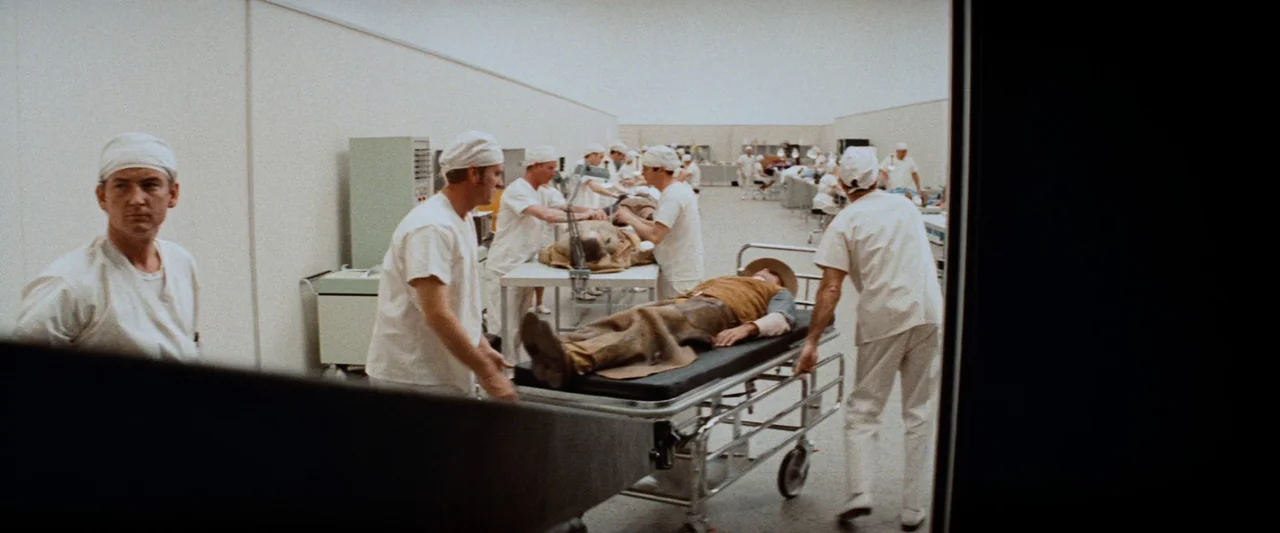 Westworld (1973) movie still: wide — A clinical, high-ceilinged room features multiple rows of stainless steel tables and white walls. Medical…
