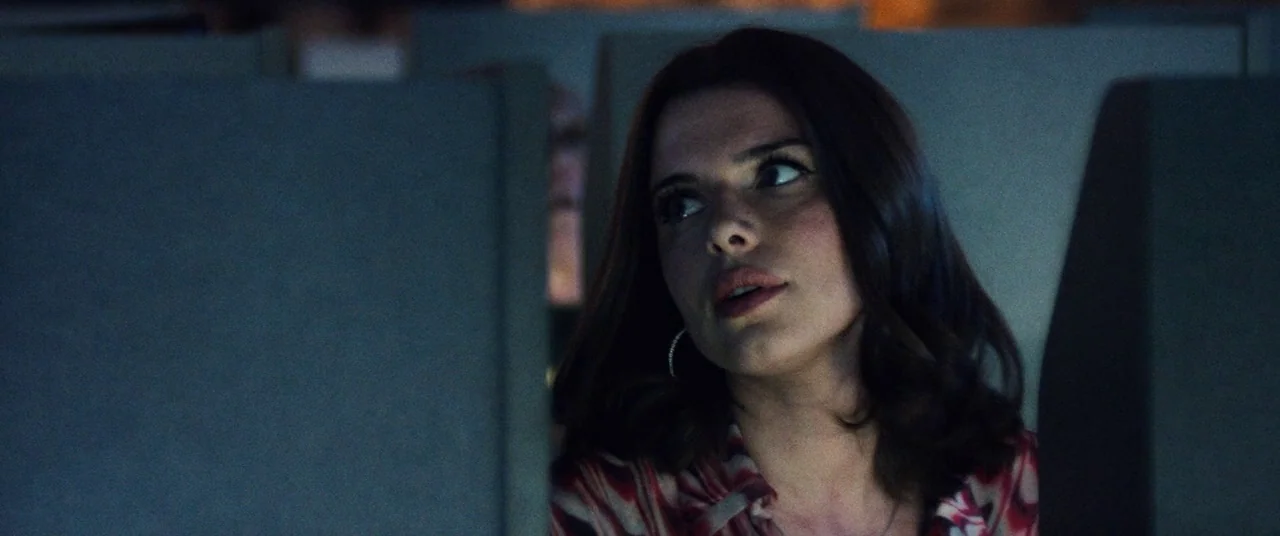 Uncut Gems (2019) movie still: closeup — The interior of an airplane cabin at night is illuminated by dim, ambient light. A young woman with dark…