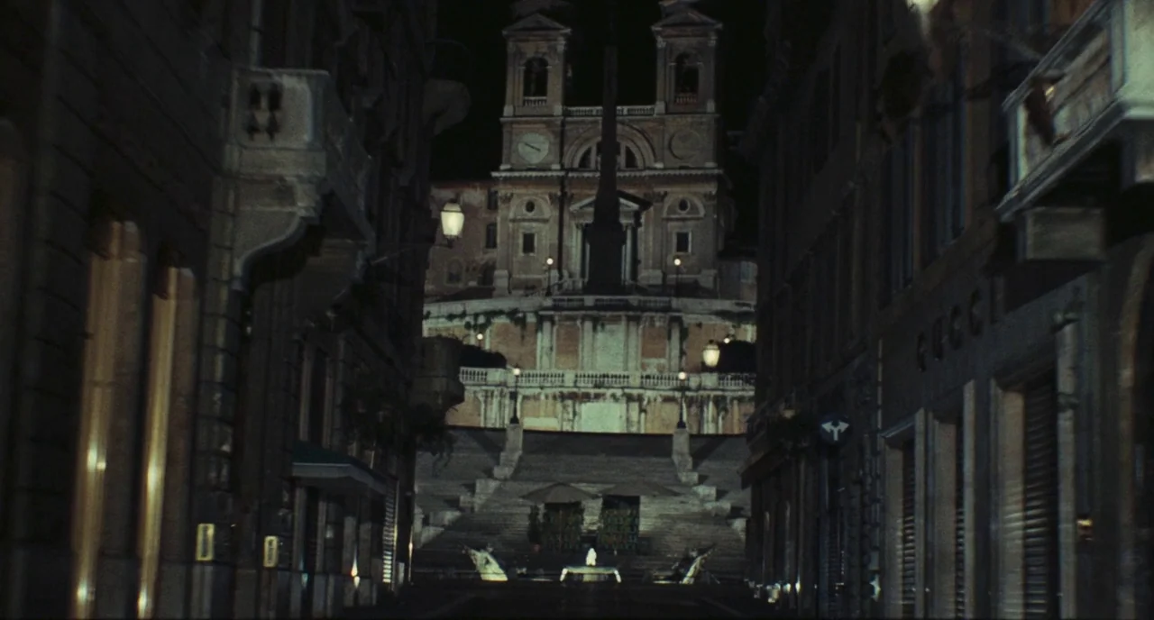 Roma (1972) movie still: establishing — The Spanish Steps in Rome are viewed at night from an adjacent narrow street. A historic church towers at…