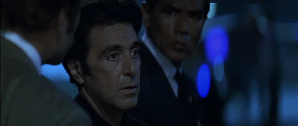 Heat (1995) movie still: medium — The interior of a dark restaurant booth with blue ambient neon lighting. Two men sit in a conversation with…