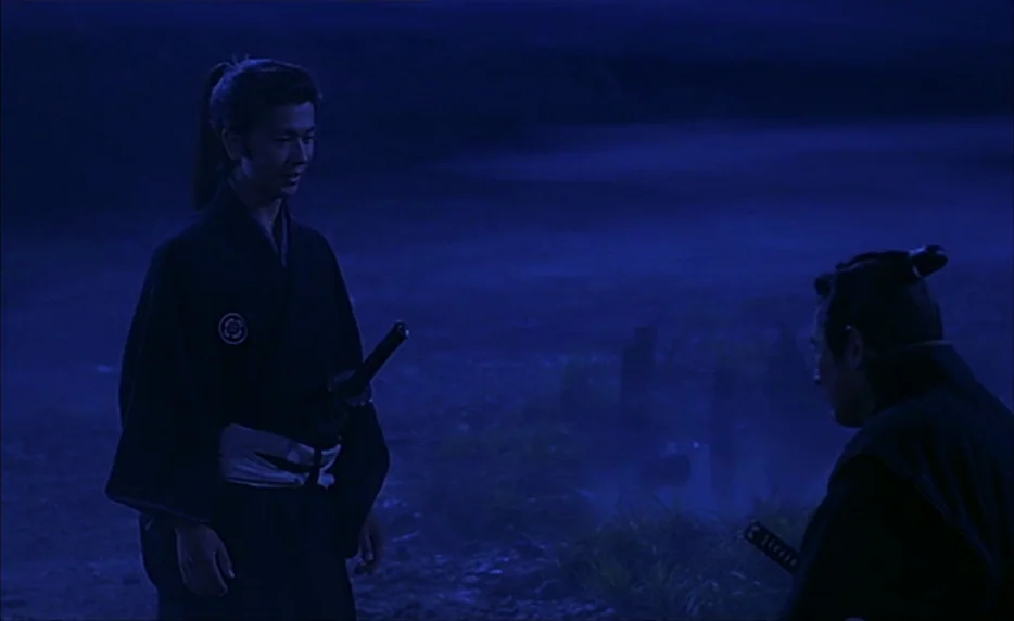 Gohatto (1999) movie still: fullbody — A dark, open landscape is illuminated by dim, monochromatic blue moonlight at night. Two men dressed in…