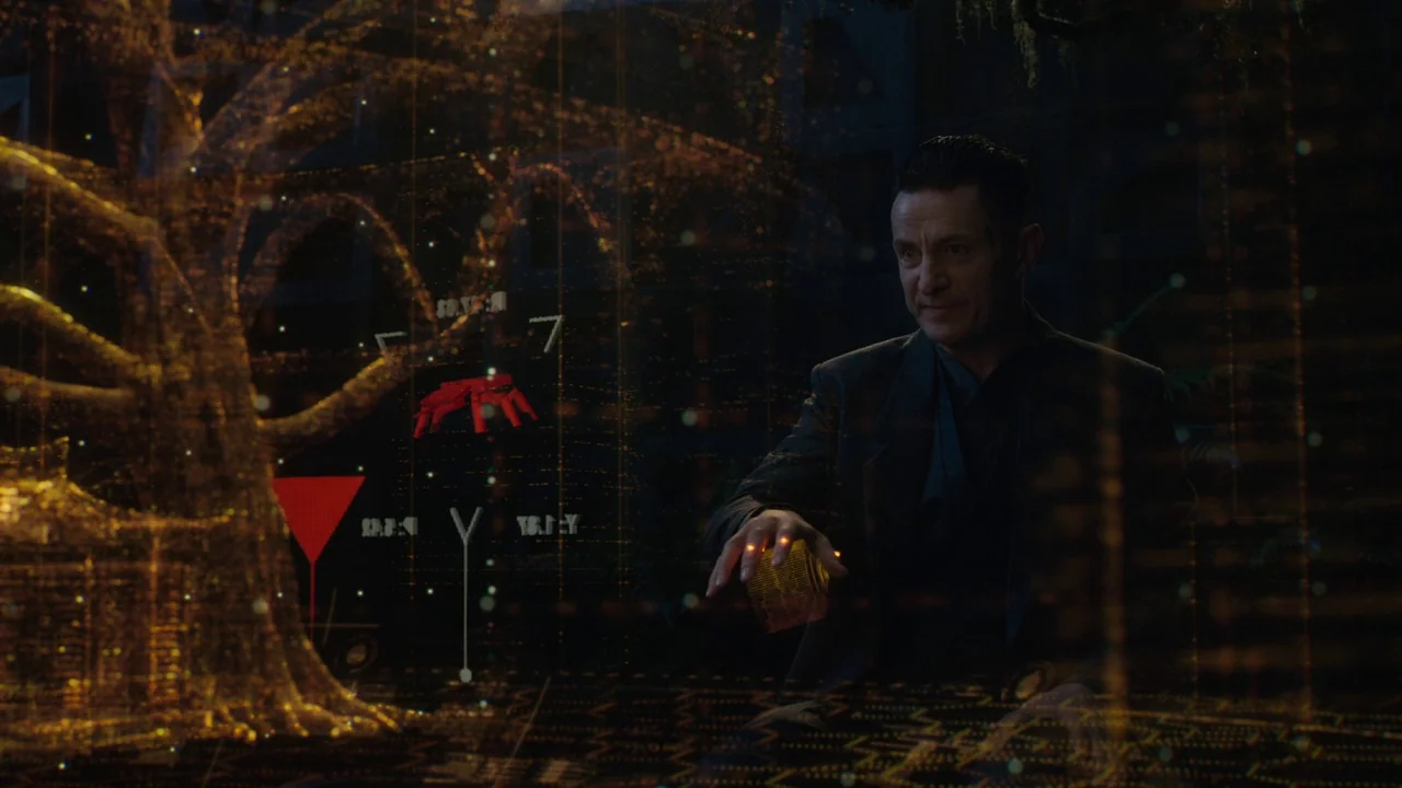 Ghost in the Shell (2017) movie still: medium — A man stands in a dark room surrounded by semi-transparent golden holographic data projections. He…