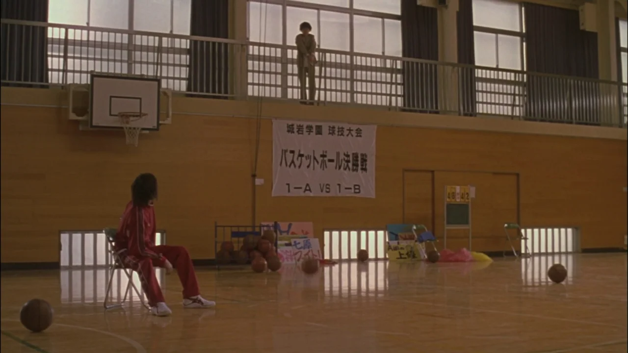 Battle Royale (2000) movie still: wide — A spacious high school gym features polished wooden floors and large windows along the back wall. One…