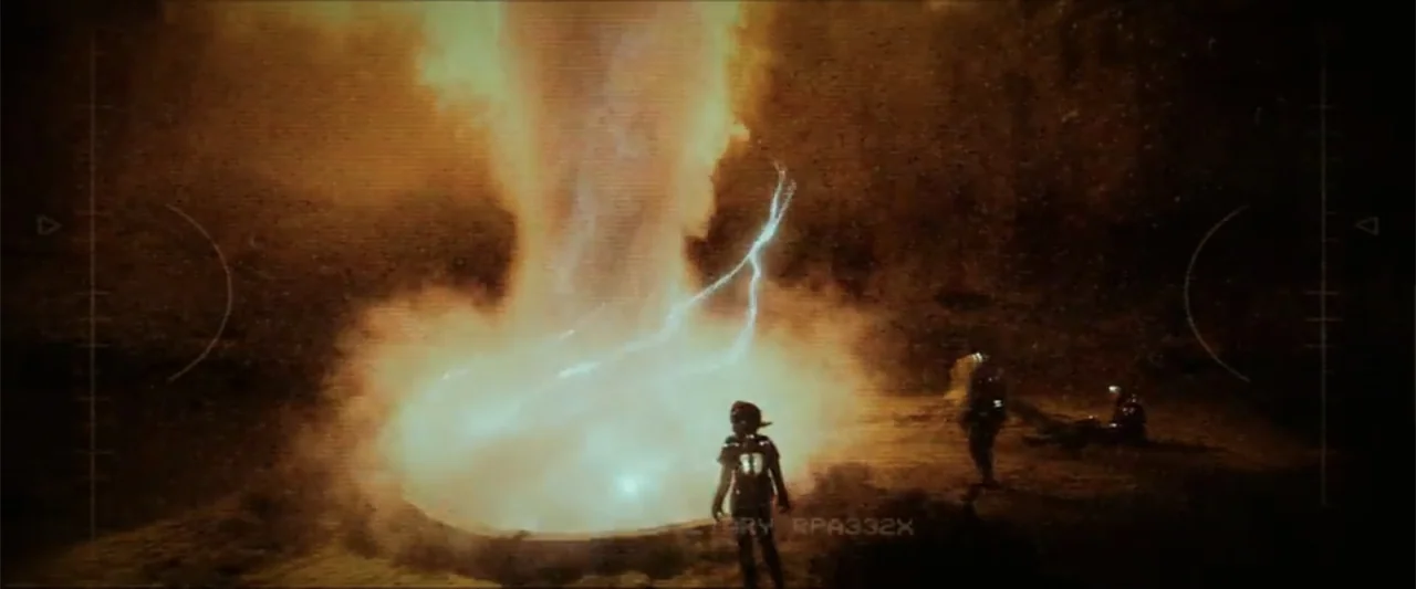 Ash (2025) movie still: wide — An open dark field features a bright electrical anomaly discharging lightning into the ground. Three figures stand at…