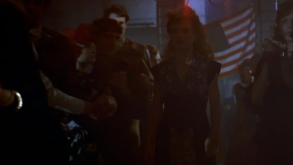 The Marriage of Maria Braun (1979) movie still: medium — A dimly lit hall features a gathering of people standing in a close formation. A woman with…