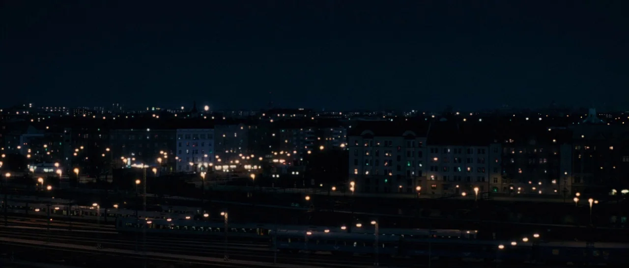 Sound of Noise (2010) movie still: establishing — A wide nighttime view shows a sprawling city skyline and railroad tracks. Numerous scattered…