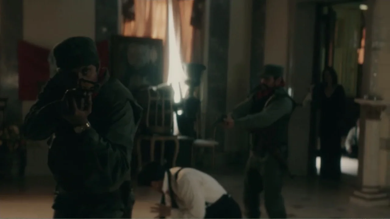 Bel Canto (2018) movie still: medium — A dimly lit room with ornate pillars and draped curtains in the background. Two armed soldiers stand in the…