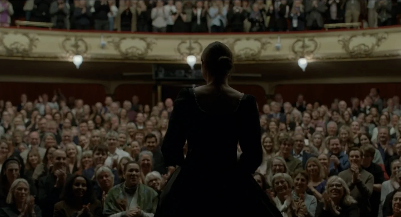 Sentimental Value (2025) movie still: medium — An opulent opera house auditorium features ornate gilded moldings and tiers of seating. A woman in a…