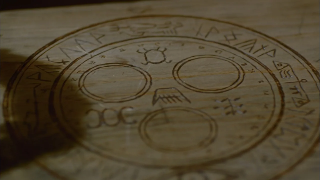 Silent Hill: Revelation 3D (2012) movie still: closeup — A close-up view of a light-colored wooden surface featuring burnt-in circular patterns and…