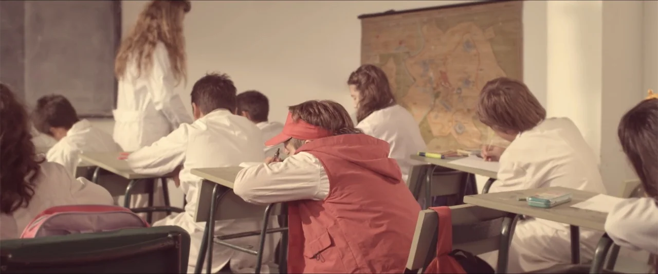 High Five (2004) movie still: medium — A group of students wearing white smocks sit at desks in a brightly lit room. They are focused on their work…