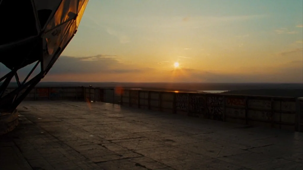We Are The Night (2010) movie still: wide — An elevated concrete platform features a graffiti-covered railing and a large metallic structure. The…