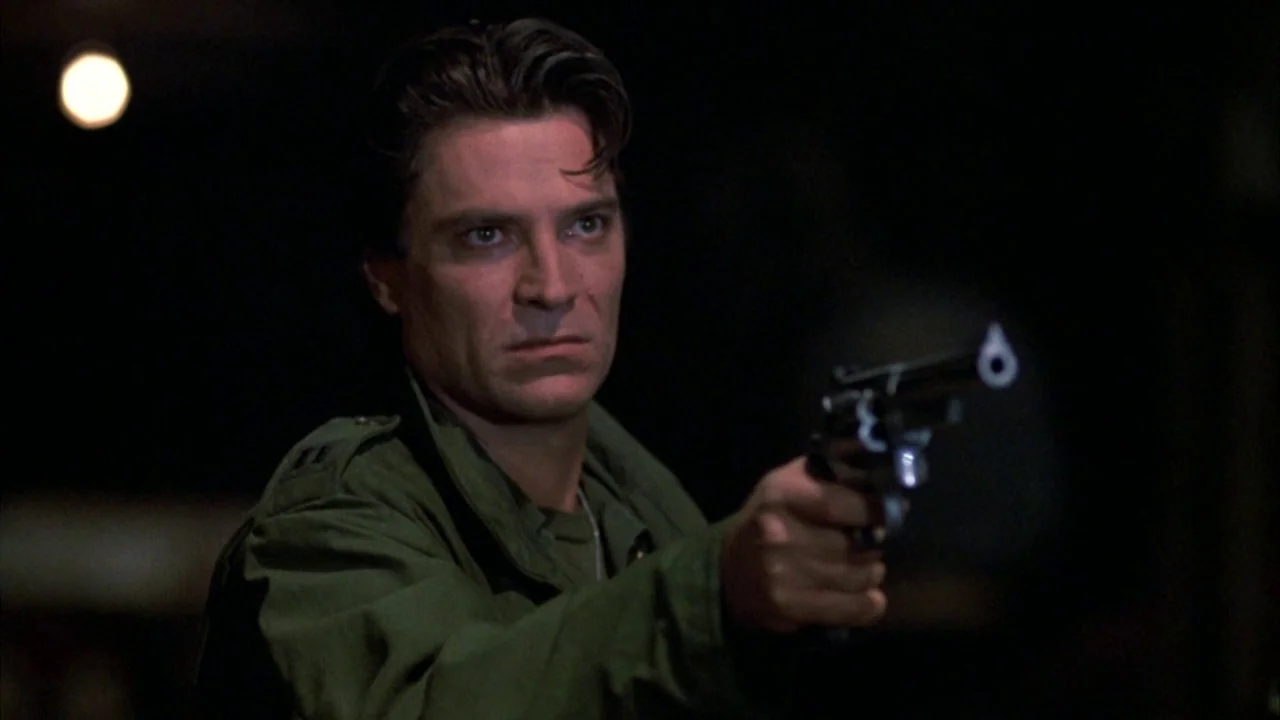 Day of the Dead (1985) movie still: medium — A man stands in a dark environment with minimal background detail. He holds a revolver pointed forward…