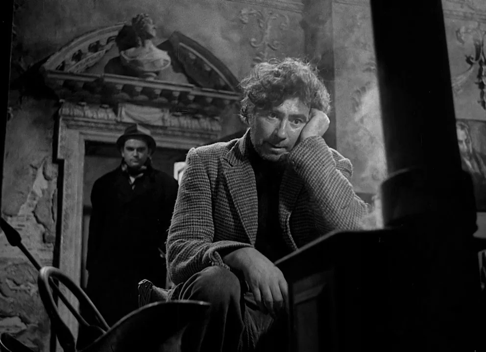 Odd Man Out (1947) movie still: medium — A dark, dilapidated interior room features decorative wall carvings and a stone bust archway. A man in a…