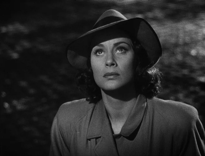 The Third Man (1949) movie still: closeup — A woman stands against a dark, out-of-focus background in high-contrast lighting. She looks upward with…