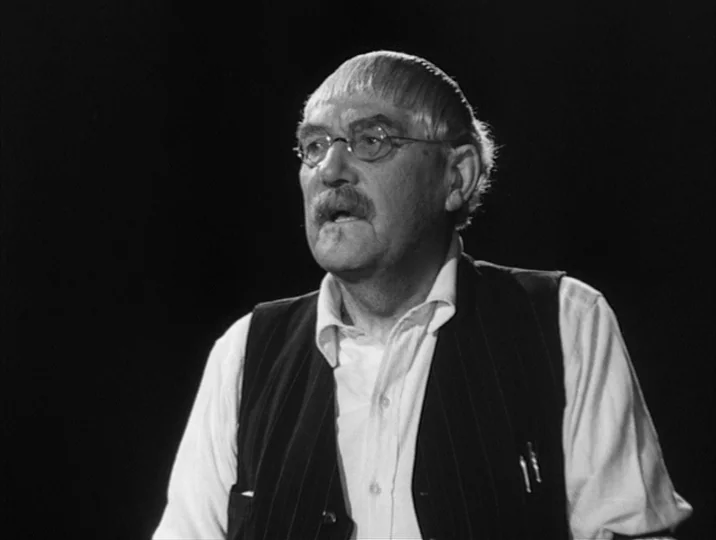 To Joy (1950) movie still: medium — An elderly man is positioned against an entirely dark, featureless black background. He looks slightly…
