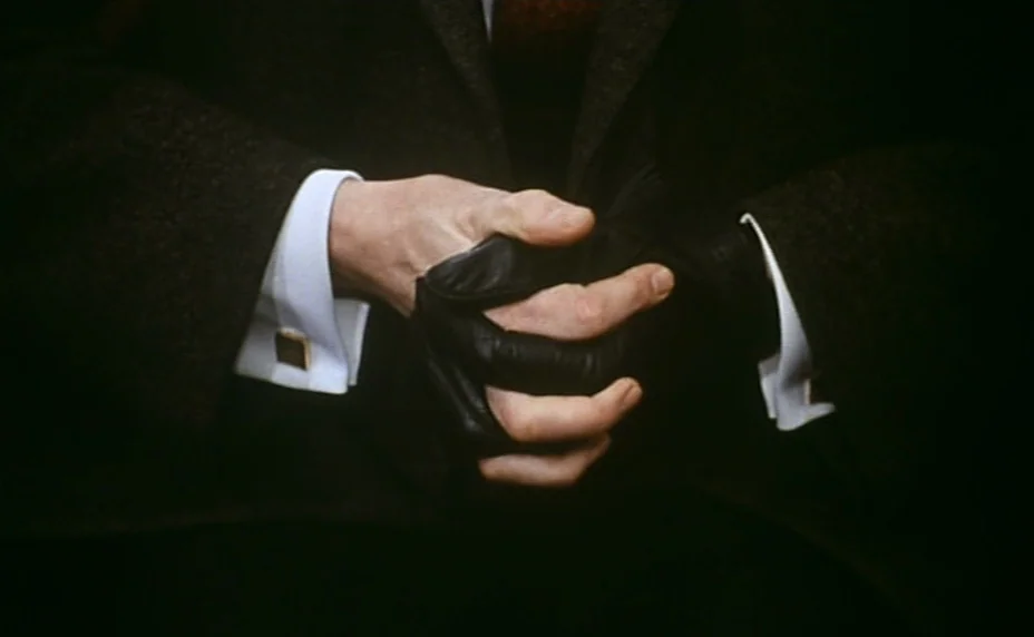 Stolen Kisses (1968) movie still: closeup — A close-up shot focuses on hands folded in a lap. A person wears a dark brown wool blazer and a white…
