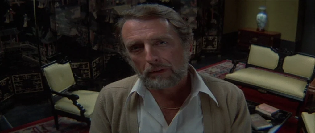 Demon Seed (1977) movie still: medium — An indoor room contains a traditional Asian-style folding screen and wooden furniture. A middle-aged man…