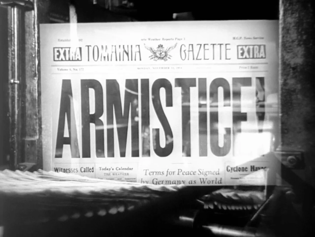 The Great Dictator (1940) movie still: closeup — A newspaper with a large headline sits behind a glass display pane. The front page of the Tomainia…
