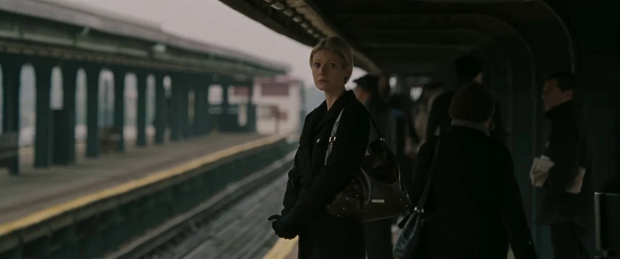 Two Lovers (2008) movie still: medium — An elevated outdoor transit stop features steel support pillars and empty tracks. A blonde woman in a dark…