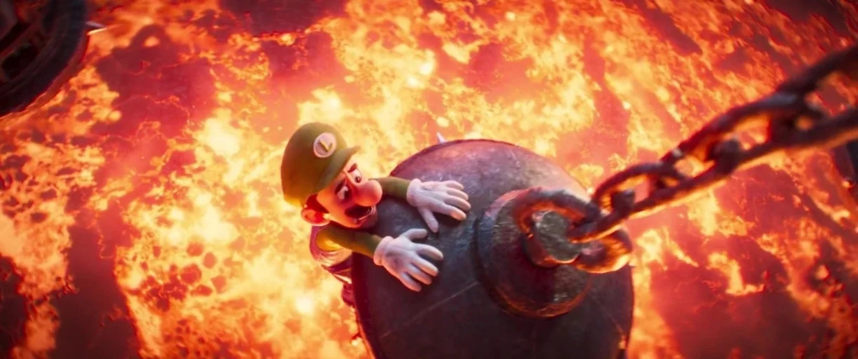 The Super Mario Bros. Movie (2023) movie still: medium — A dark, metallic spiked ball hangs above a bubbling, bright orange river of lava. Luigi, a…
