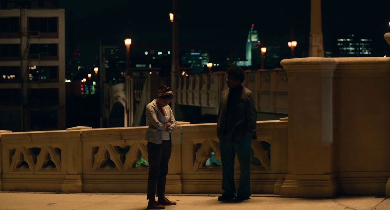 Roman J. Israel, Esq. (2017) movie still: wide — A concrete bridge at night overlooks a city with illuminated distant office buildings. A man and a…