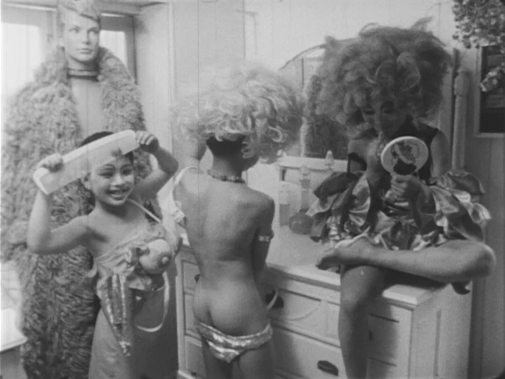 Emperor Tomato Ketchup movie still: medium — A bedroom contains a dresser with a mirror, a mannequin, and three young children. They are dressed in…