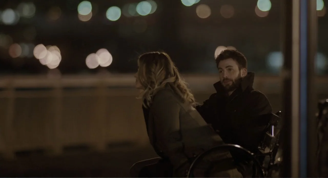 Before We Go (2014) movie still: medium — A night scene outdoors with two people sitting on a bench near water. A man with a beard sits beside a…