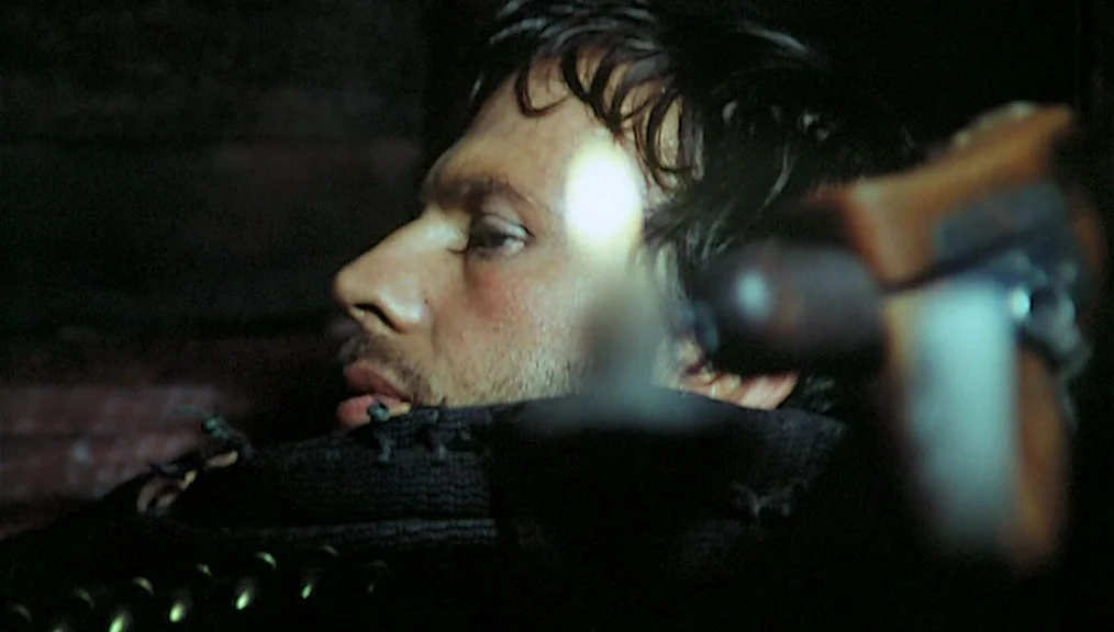 The Great Silence (1968) movie still: closeup — A dimly lit room with dark surroundings hides details of the surrounding space. A man with…