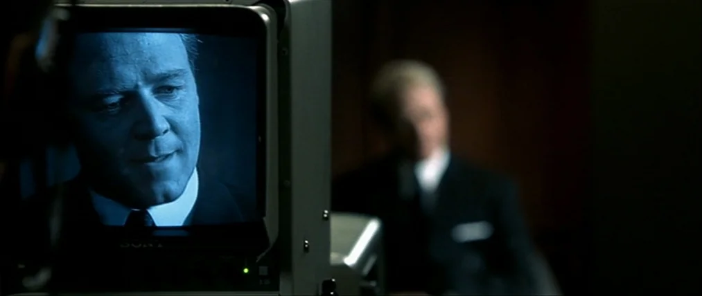 The Insider (1999) movie still: closeup — A man is displayed on a Sony television screen in a darkened room. In the out-of-focus background, another…