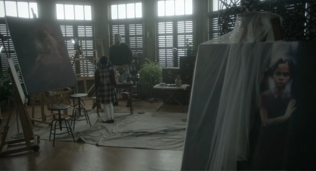 Orphan: First Kill (2022) movie still: wide — An art studio features wooden floors covered with canvas tarps and several standing easels. A young…