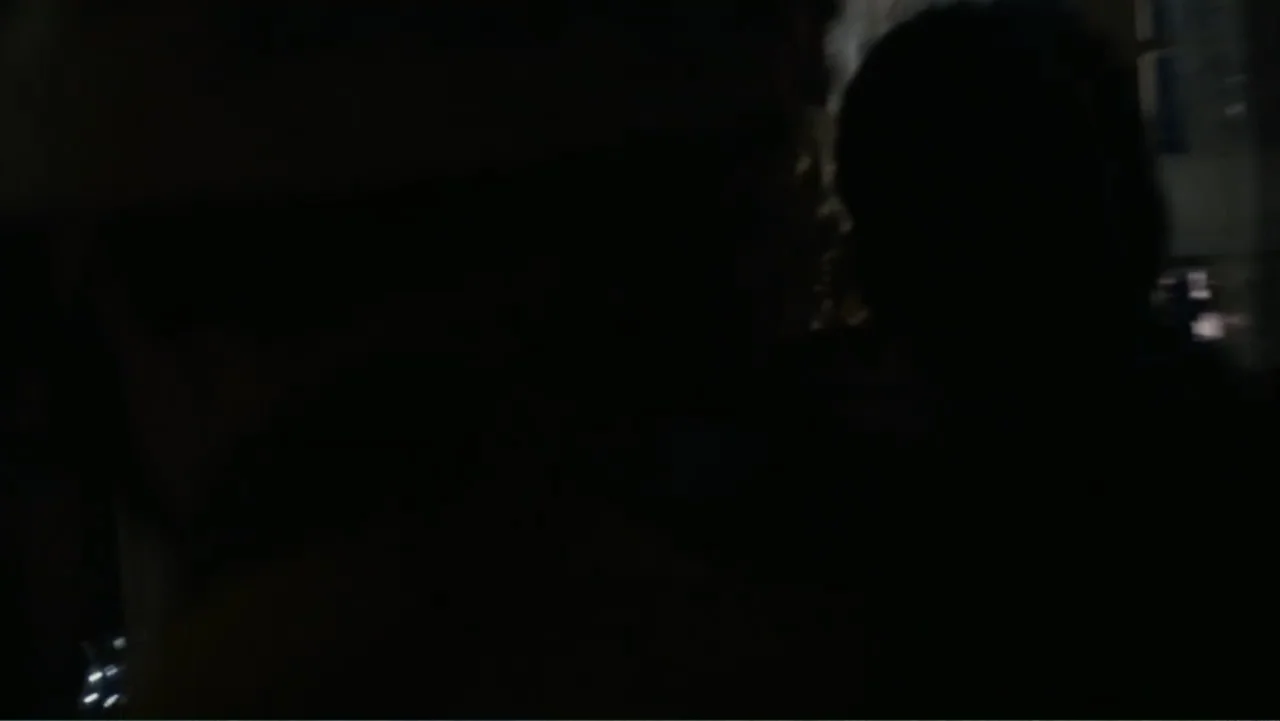 Quarantine (2008) movie still: closeup — A dimly lit interior space with very little visible detail. Two figures stand in close proximity to one…
