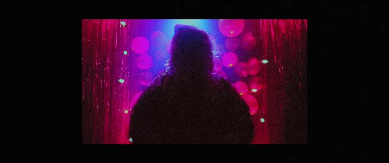 Christmas Bloody Christmas (2022) movie still: medium — A dark space decorated with hanging red foil curtains and numerous circular party balloons.…