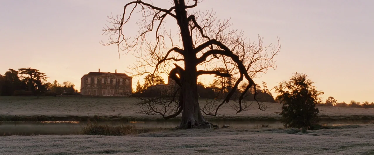 Far from the Madding Crowd (2015) movie still: establishing — A grassy meadow leads to a body of water with a large manor house visible. A lone…
