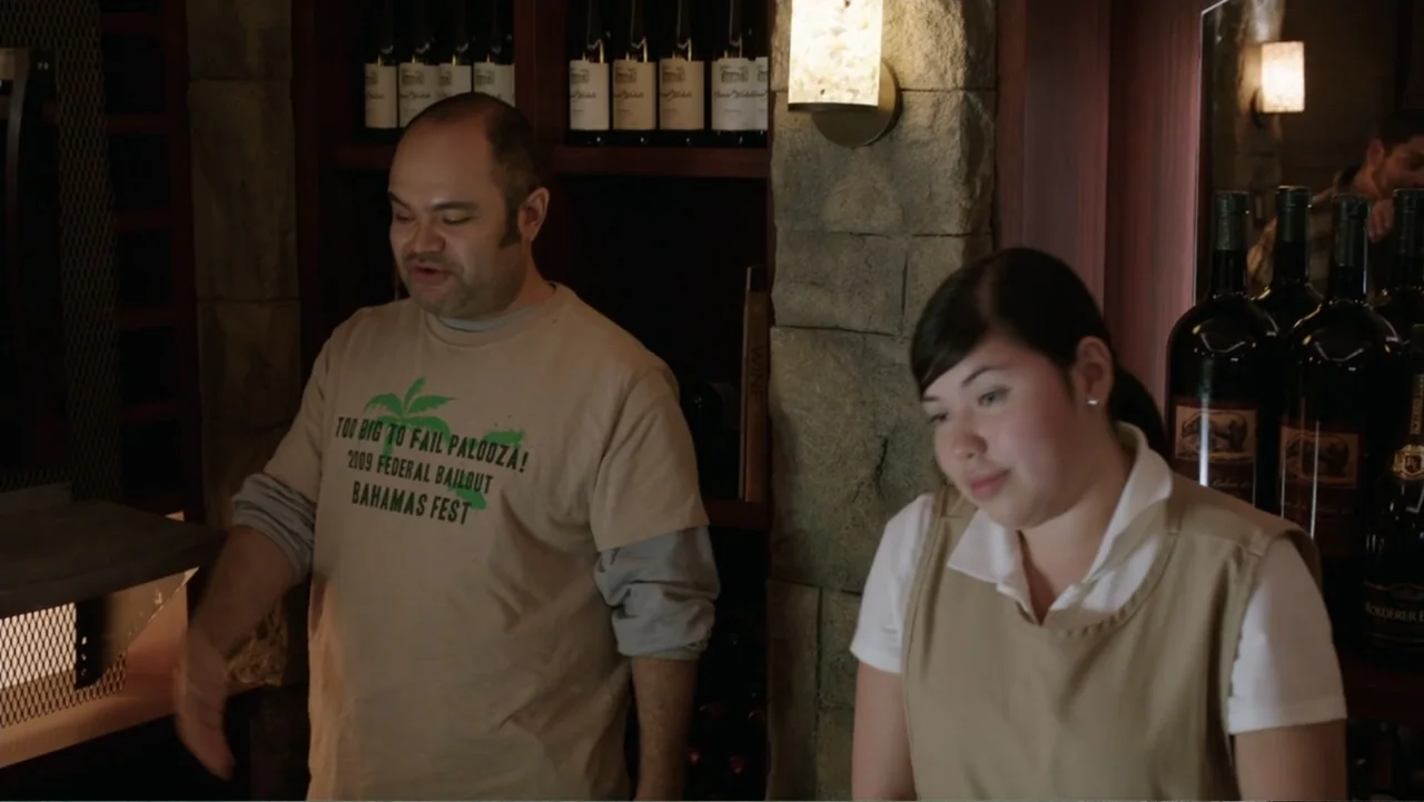 Get Hard (2015) movie still: medium — A retail wine shop interior features stone walls and shelves stocked with wine bottles. A man in a graphic…