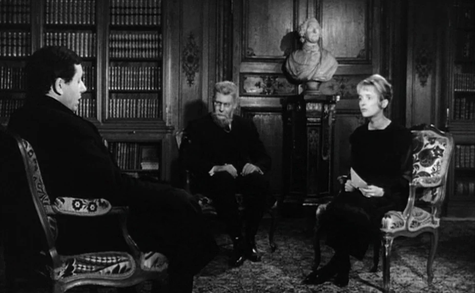 Judex (1966) movie still: medium — A dimly lit room with floor-to-ceiling wooden bookshelves and a marble bust on a pedestal. Three people sit in…