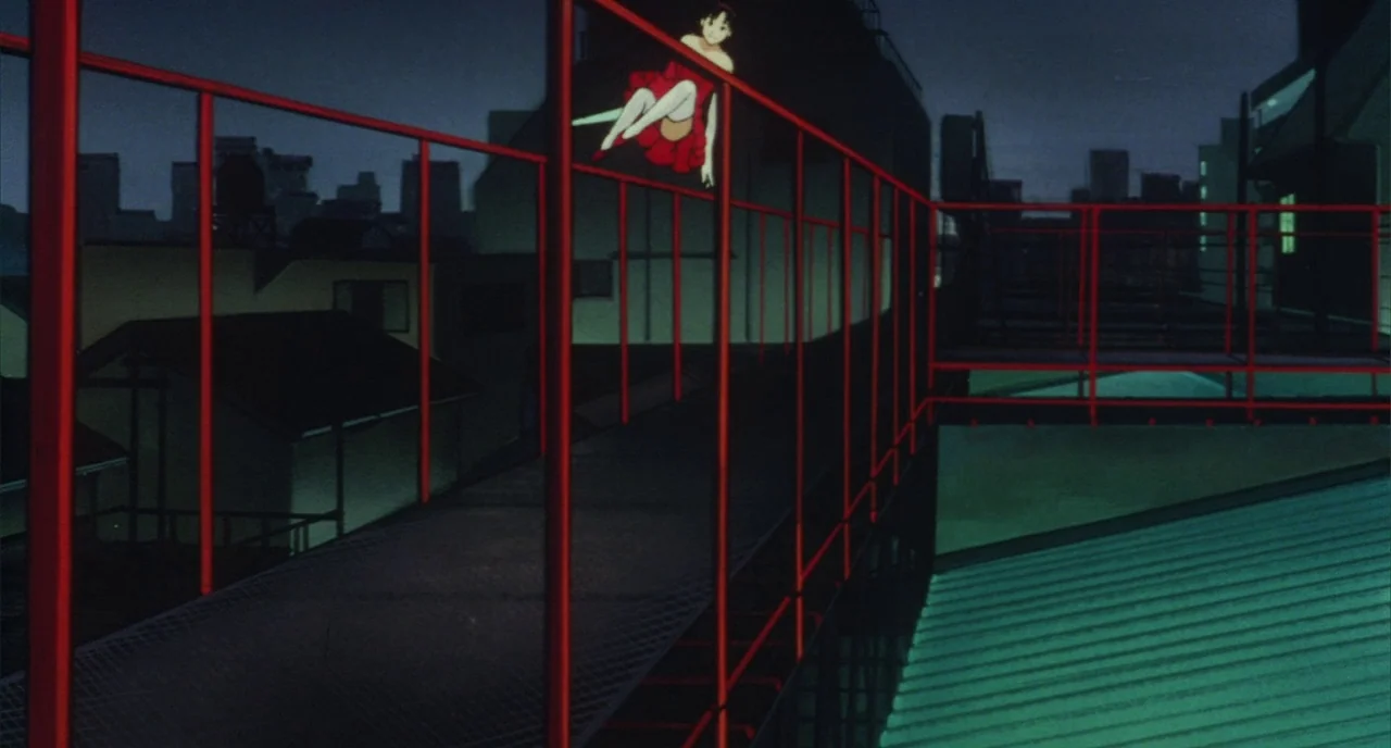 Perfect Blue (1997) movie still: wide — A dark urban rooftop at night features a prominent grid of red metal railings. A young woman in a red dress…
