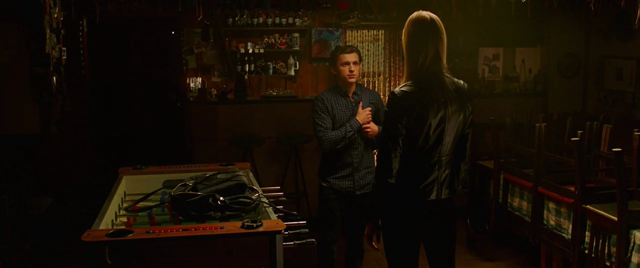 Spider-Man: Far From Home (2019) movie still: medium — A dimly lit pub with wooden decor and a foosball table in the foreground. A young man stands…