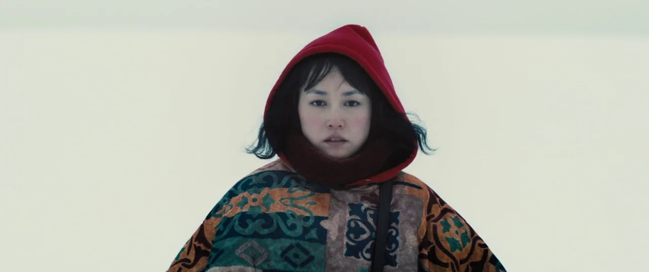 Kumiko the Treasure Hunter (2014) movie still: medium — A person stands in a vast, featureless expanse covered in white snow. The subject wears a…