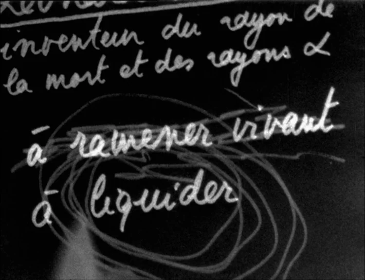 Alphaville (1965) movie still: closeup — A dark blackboard features handwritten French text in white chalk script. Some phrases are crossed out with…